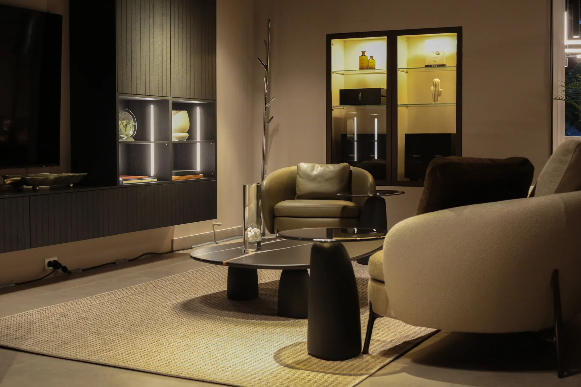 Sala lounge Poliform en Bogotá con sillón mostaza en cuero, sofá boucle blanco y librería con iluminación integrada · diseño interior por César Serrano