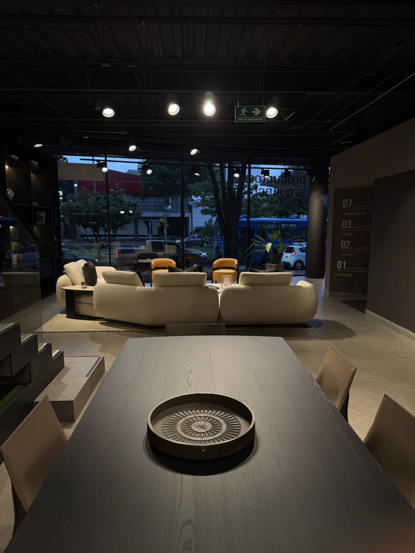 Mesa de comedor en madera y sala Poliform con vista a la fachada del showroom de Productos Arquitectónicos en Bogotá