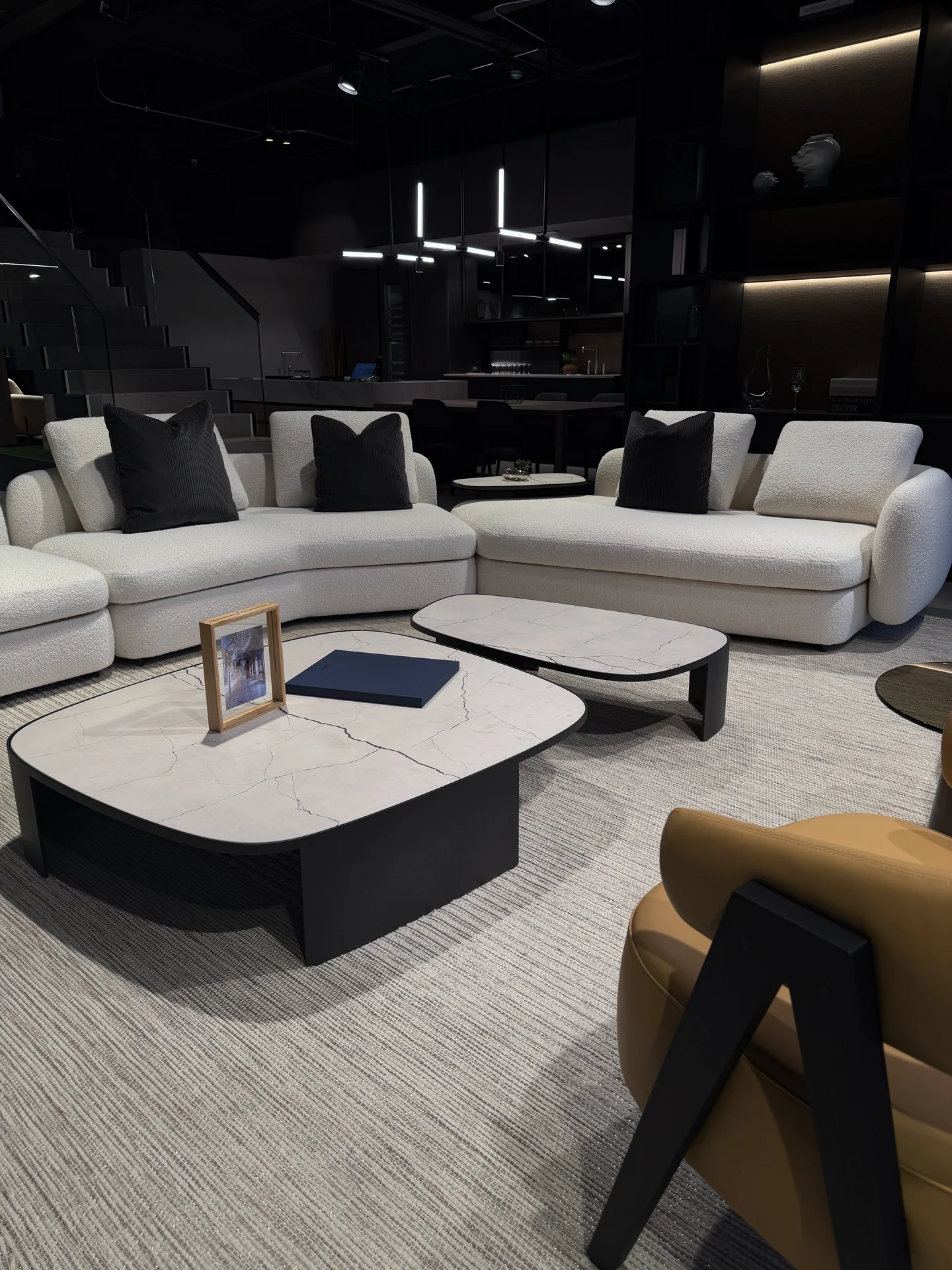 Sala Poliform con sofás modulares blancos en boucle, mesas centro en mármol y sillón mostaza · showroom Productos Arquitectónicos en Bogotá